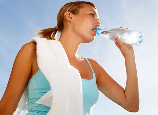 Mujer bebiendo agua y haciendo ejercicio